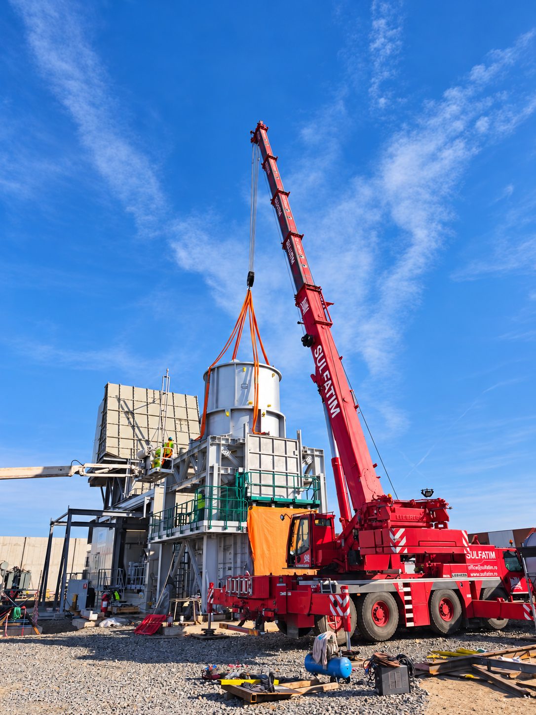 Retehnologizare parc industrial Nova Power, Campia Turzii: Tronson cilindric suspendat in chingi, ghidat de montatori spre structura metalica a cosului