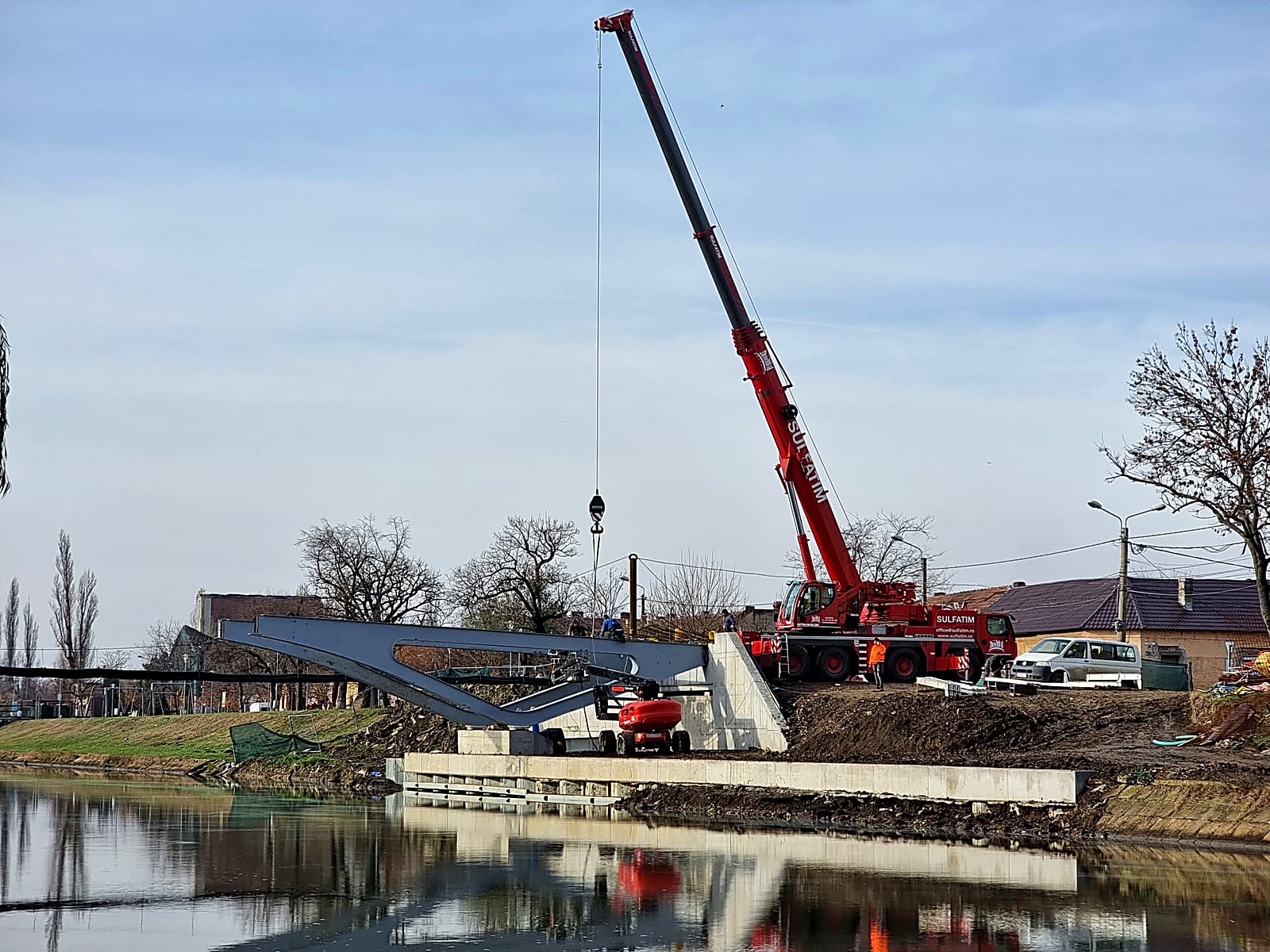 Pasarela Gelu: Automacara Liebherr Sulfatim ridica un tablier metalic deasupra apei, pe timpul montajului noului pod peste Bega.